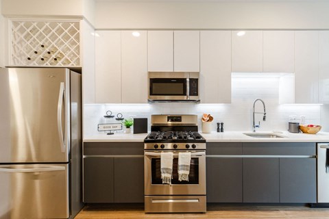 a kitchen with stainless steel appliances and white cabinets at One Ten Apartments, Jersey City